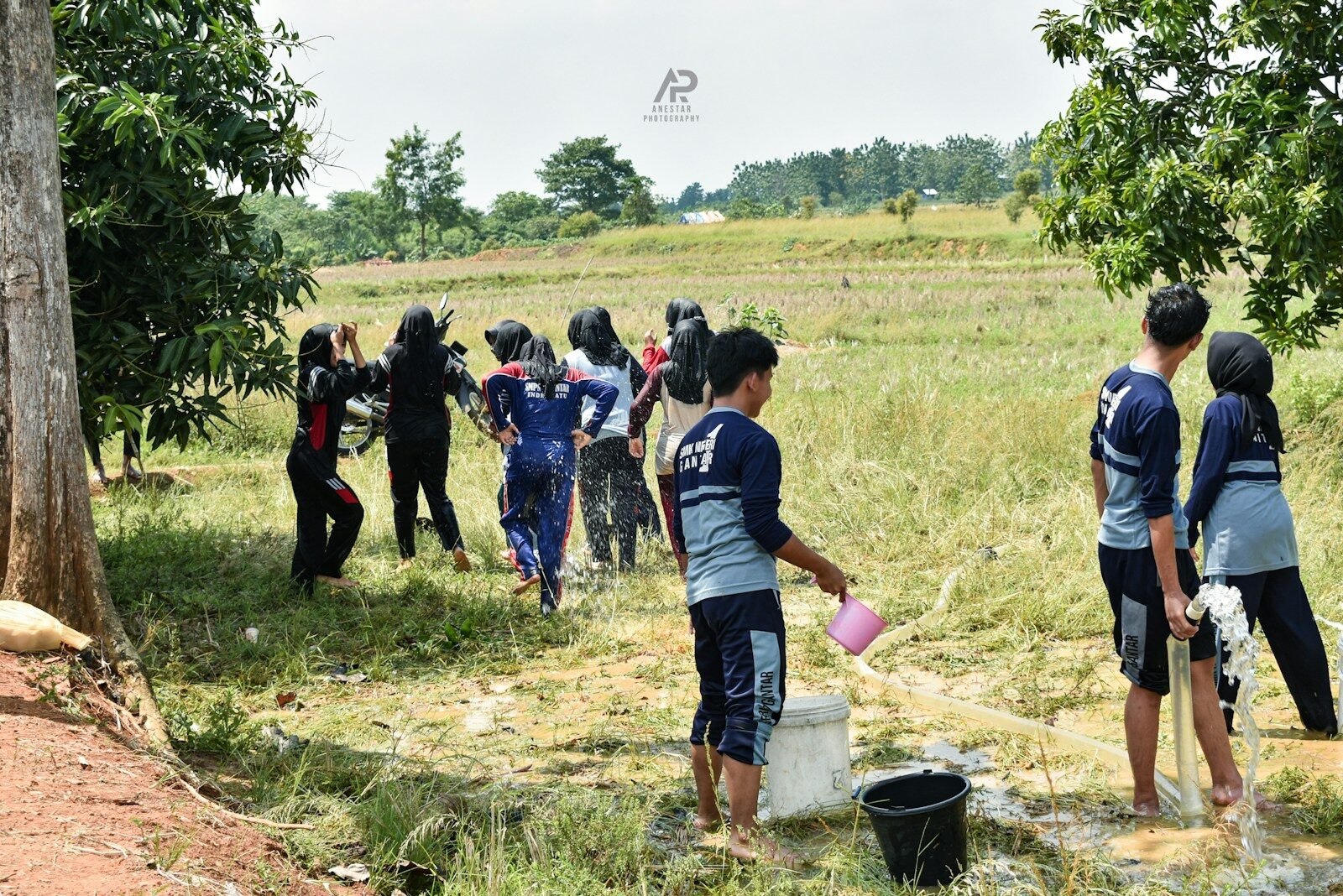 Group of young people gathered outdoors by water.